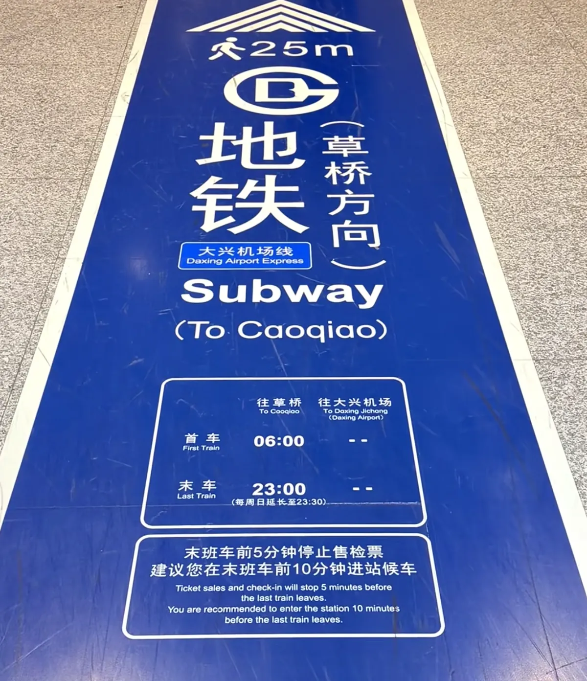 Blue floor sign at Beijing Daxing Airport pointing to the subway toward Caoqiao