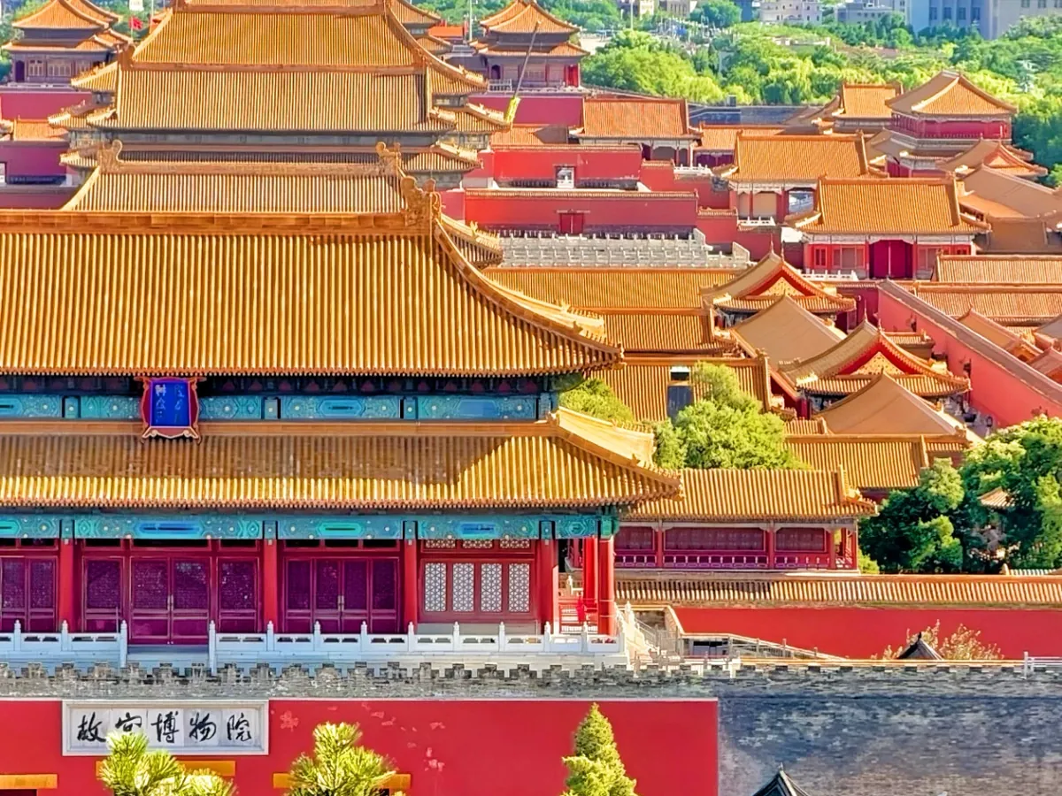 Golden roofs of the Forbidden City above the red wall, with the Palace Museum sign