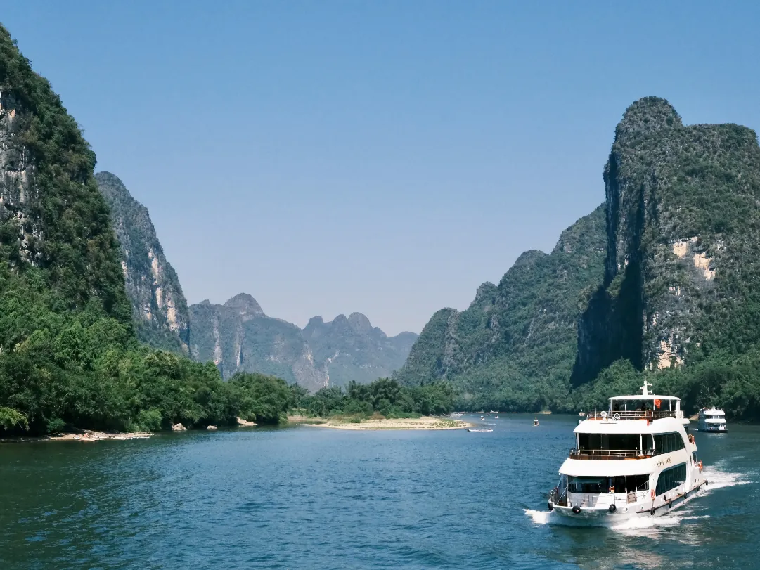 A Li River cruise boat sailing between steep karst cliffs between Guilin and Yangshuo