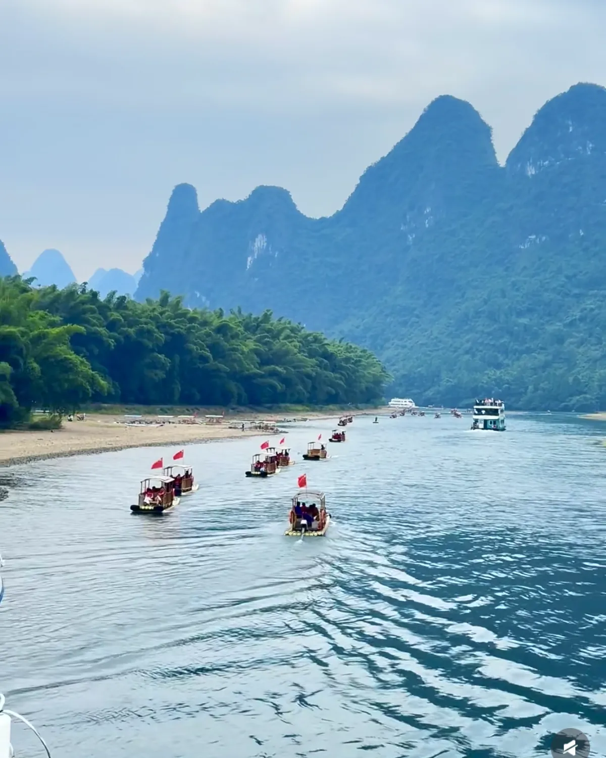 View from the open deck of a Li River cruise boat towards bamboo rafts and karst peaks