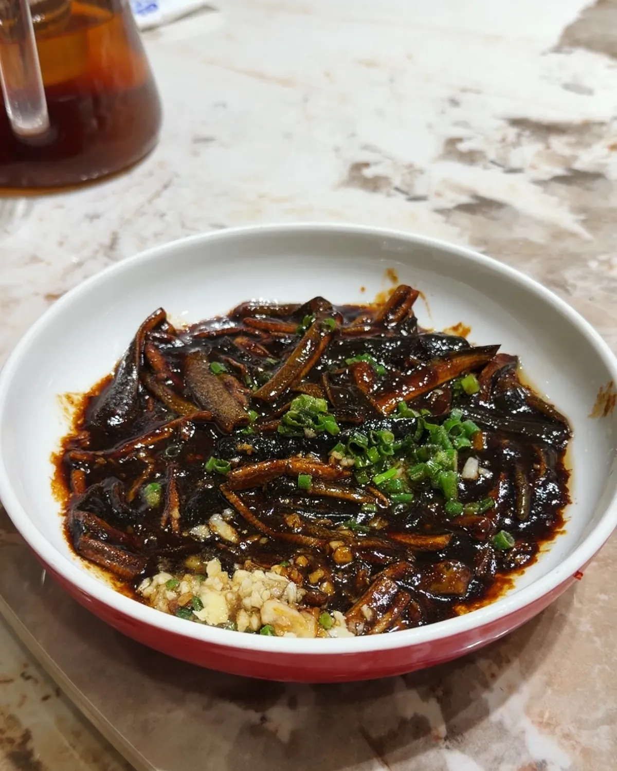 A bowl of Shanghai-style eel in dark soy sauce topped with chopped scallions