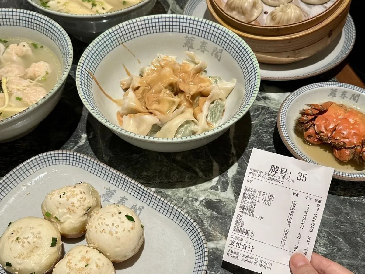 Xiaolongbao in a bamboo steamer, sesame-topped shengjianbao, wontons and a hairy crab on a table at a Shanghai snack restaurant