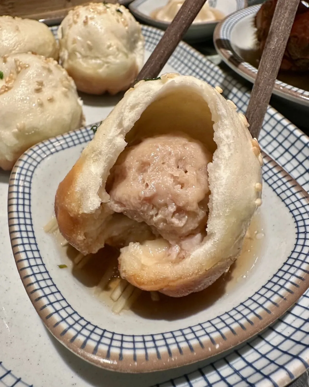 A shengjianbao bitten open to show the pork filling and soup inside its crisp browned base