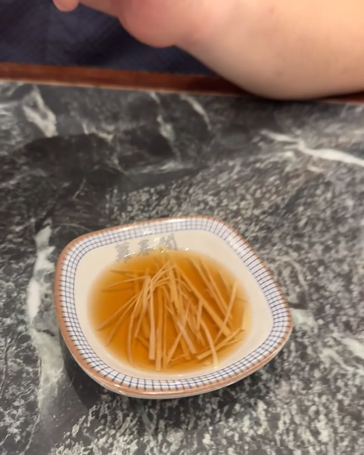 A small dish of black vinegar with shredded ginger for dipping soup dumplings