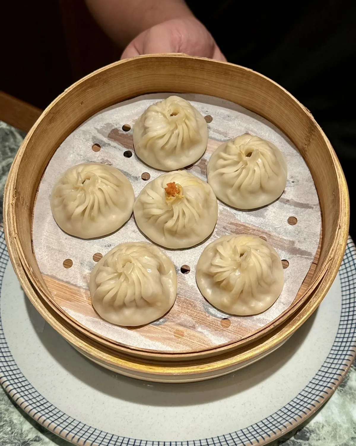 Six pleated xiaolongbao in a bamboo steamer