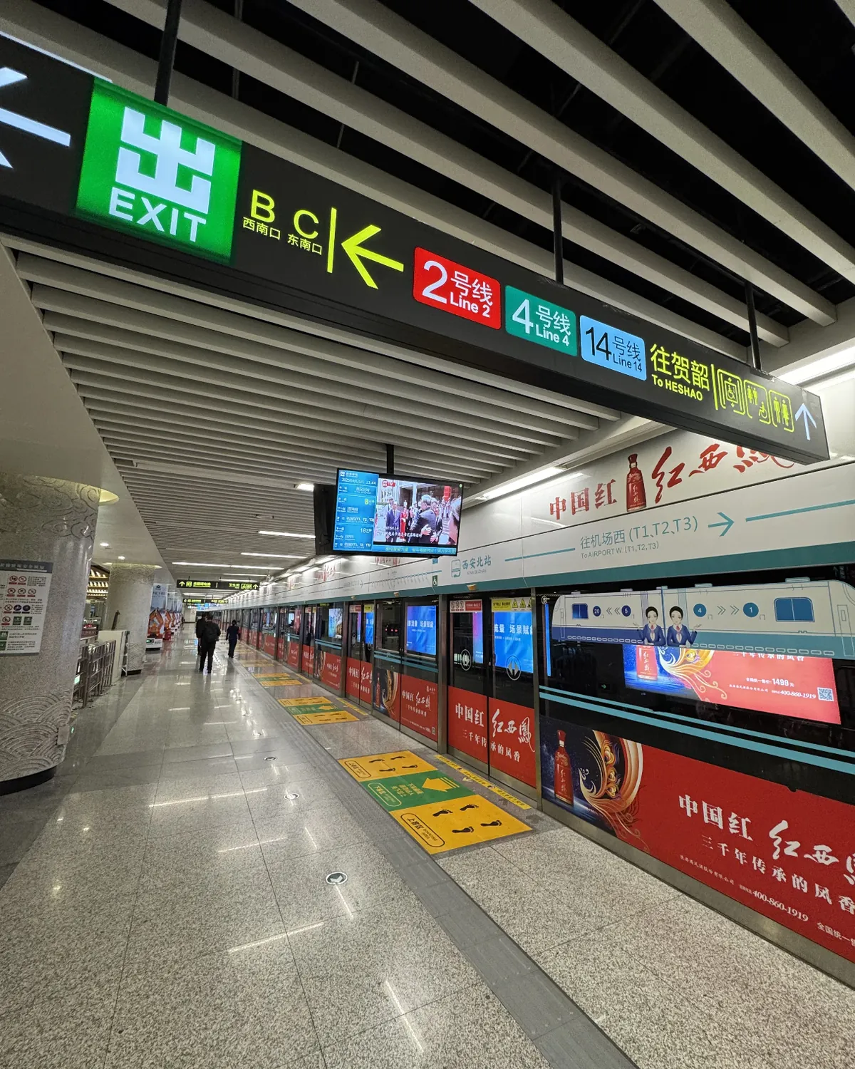 The Line 14 platform at Xi'an North with overhead signs for the exits, Lines 2 and 4, and Airport West